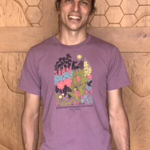 Alex modeling our new eggplant colored t-shirt with a five color design depicting various flowers, a beekeeper, a hive, several native plants, a hummingbird, butterfly and bees.